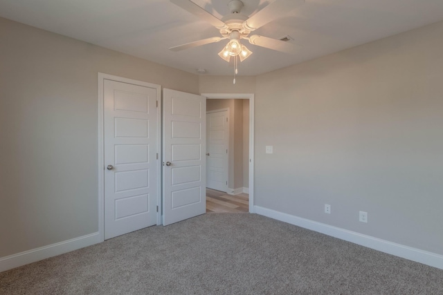 unfurnished bedroom featuring ceiling fan, light carpet, and a closet