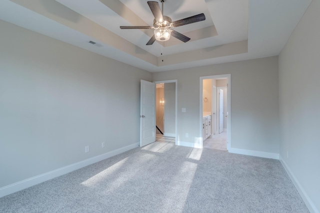 spare room featuring ceiling fan, light carpet, and a tray ceiling