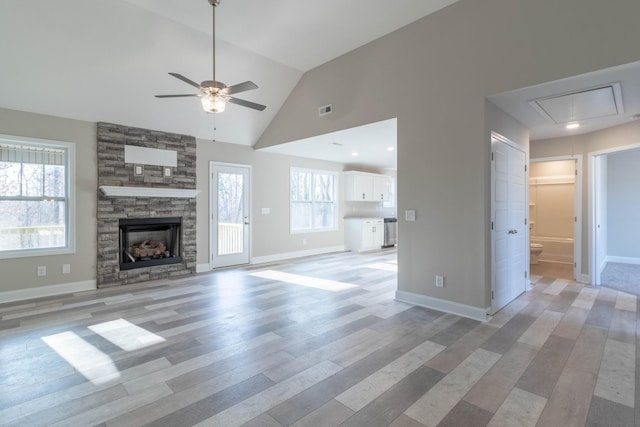 unfurnished living room with light hardwood / wood-style floors, a stone fireplace, ceiling fan, and lofted ceiling