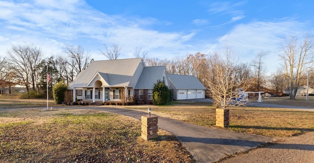 view of front facade featuring a front yard, a porch, a garage, and an outdoor structure