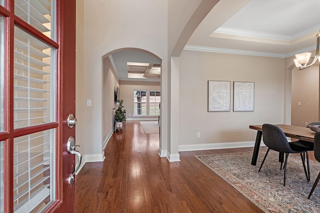 interior space with dark wood-type flooring, coffered ceiling, an inviting chandelier, a tray ceiling, and ornamental molding