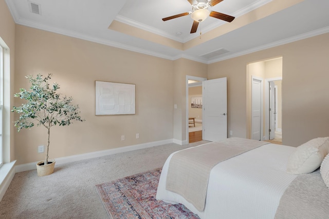 bedroom featuring ceiling fan, a raised ceiling, ensuite bathroom, light carpet, and ornamental molding