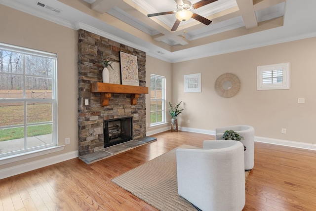 living room with ornamental molding, a stone fireplace, ceiling fan, and coffered ceiling