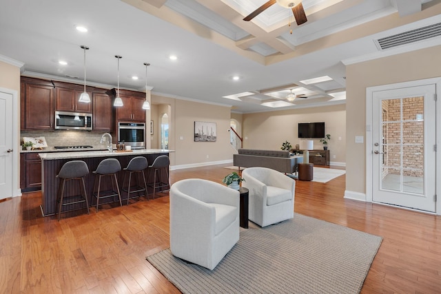 living room with ornamental molding, coffered ceiling, ceiling fan, beam ceiling, and light hardwood / wood-style floors