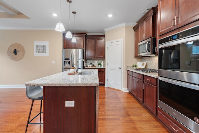 kitchen with backsplash, a center island with sink, light stone countertops, and stainless steel appliances