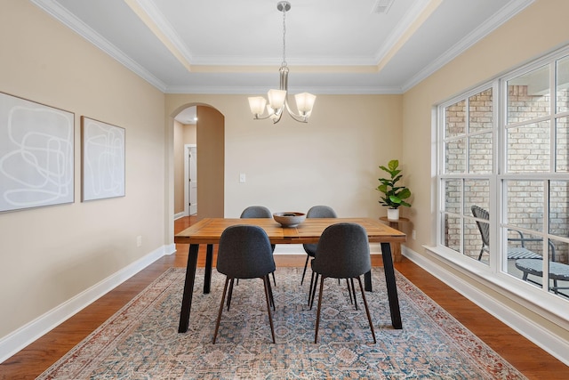 dining space featuring a tray ceiling, crown molding, and a notable chandelier