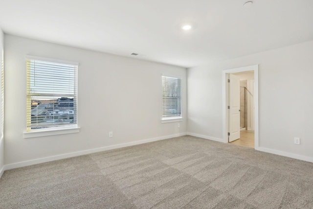 carpeted empty room with plenty of natural light, visible vents, and baseboards