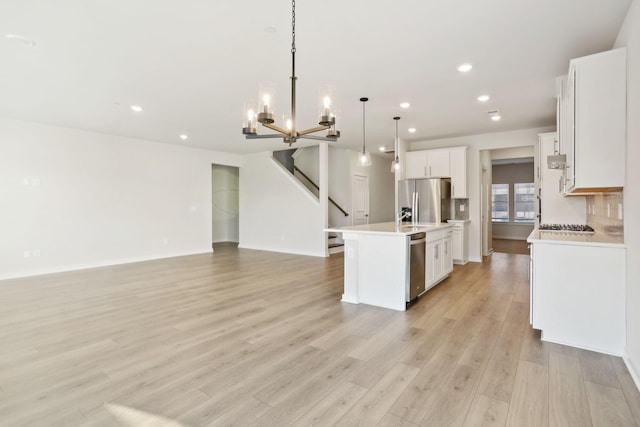 kitchen featuring open floor plan, appliances with stainless steel finishes, light countertops, and light wood-type flooring