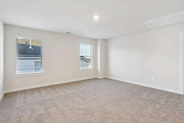 unfurnished room with attic access, carpet flooring, visible vents, and baseboards