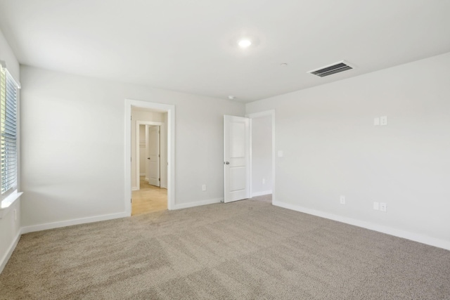 spare room with visible vents, light colored carpet, plenty of natural light, and baseboards