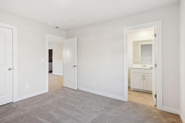 unfurnished bedroom with light colored carpet, baseboards, ensuite bathroom, and a sink