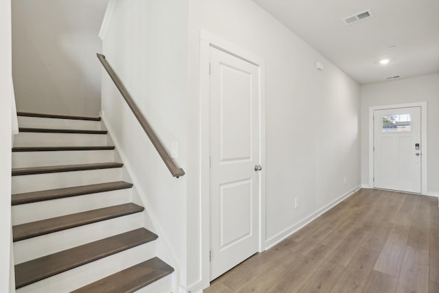 foyer entrance with visible vents, baseboards, stairway, recessed lighting, and wood finished floors