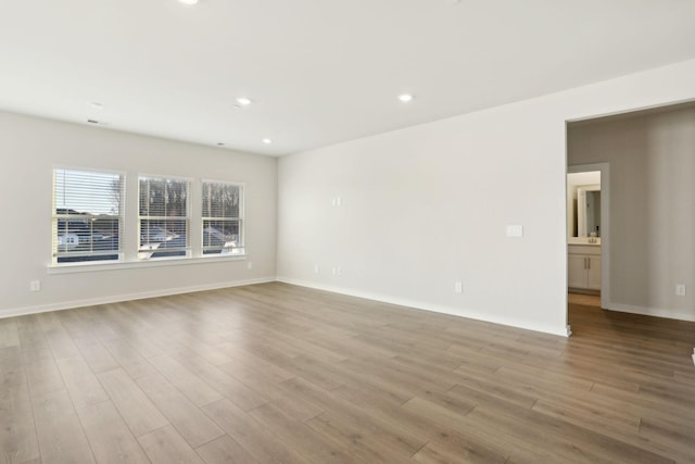 empty room with recessed lighting, baseboards, and wood finished floors