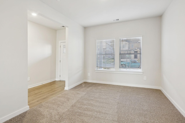 carpeted spare room featuring visible vents and baseboards