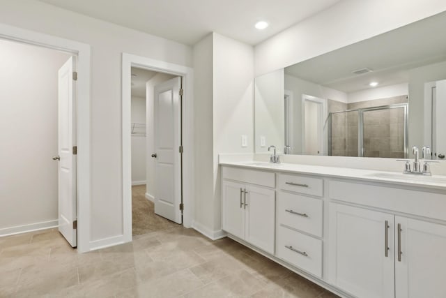 bathroom with a shower stall, a spacious closet, double vanity, and a sink