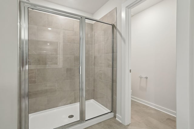 full bathroom with tile patterned flooring, a shower stall, toilet, and baseboards