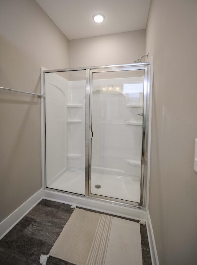 bathroom featuring a shower with shower door and wood-type flooring