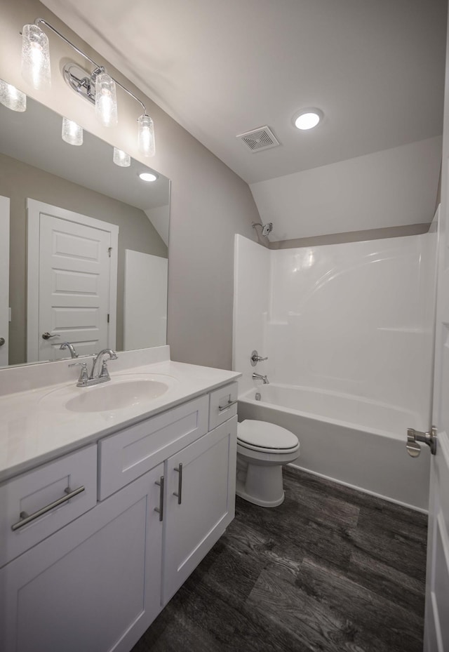 full bathroom featuring hardwood / wood-style floors, vanity, lofted ceiling, toilet, and shower / bathtub combination