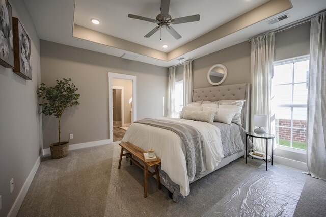 bedroom with connected bathroom, a tray ceiling, ceiling fan, and carpet floors