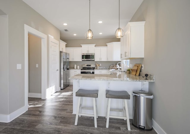 kitchen with white cabinetry, sink, kitchen peninsula, decorative light fixtures, and appliances with stainless steel finishes