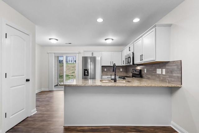 kitchen featuring kitchen peninsula, appliances with stainless steel finishes, decorative backsplash, sink, and white cabinetry