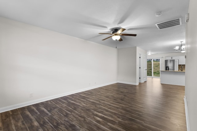 unfurnished living room featuring ceiling fan with notable chandelier and dark wood-type flooring