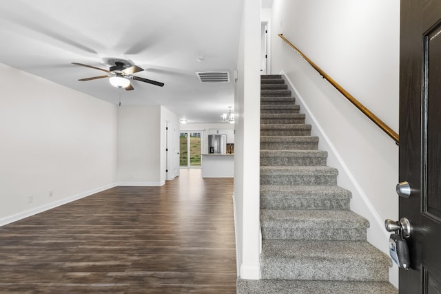 staircase with hardwood / wood-style flooring and ceiling fan with notable chandelier