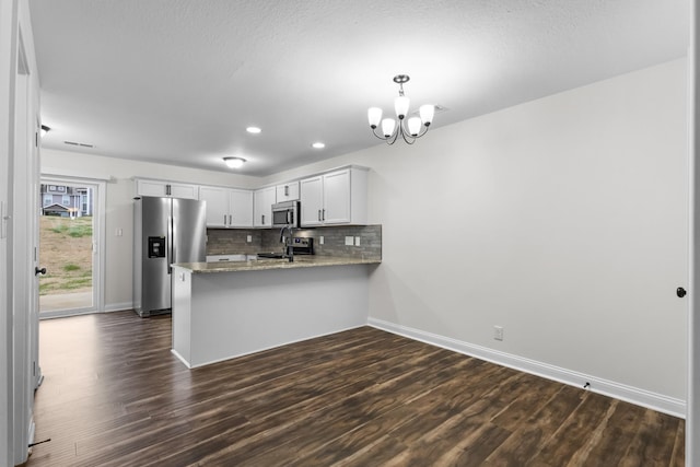 kitchen with white cabinetry, stainless steel appliances, kitchen peninsula, a chandelier, and pendant lighting