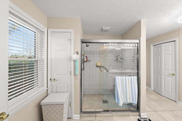 bathroom featuring tile patterned floors, a shower with door, and a textured ceiling