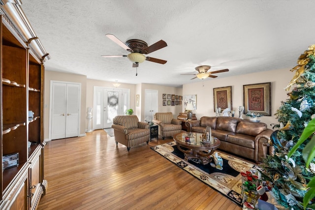 living room featuring ceiling fan, a textured ceiling, and light hardwood / wood-style flooring