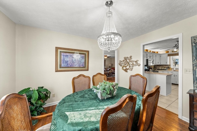 dining space with light hardwood / wood-style floors, a textured ceiling, and an inviting chandelier