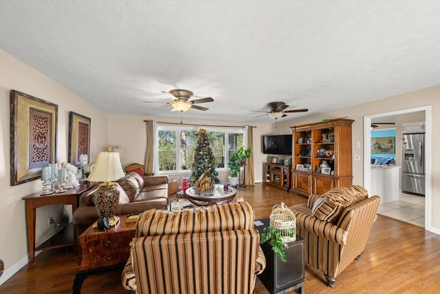 living room featuring ceiling fan, wood-type flooring, and a textured ceiling