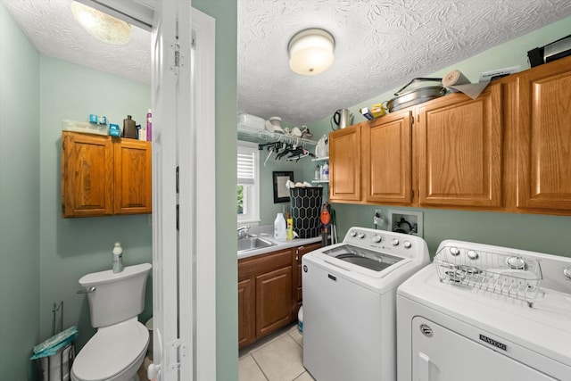 washroom with sink, cabinets, separate washer and dryer, a textured ceiling, and light tile patterned floors