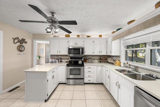 kitchen with white cabinetry, tasteful backsplash, kitchen peninsula, light tile patterned floors, and appliances with stainless steel finishes