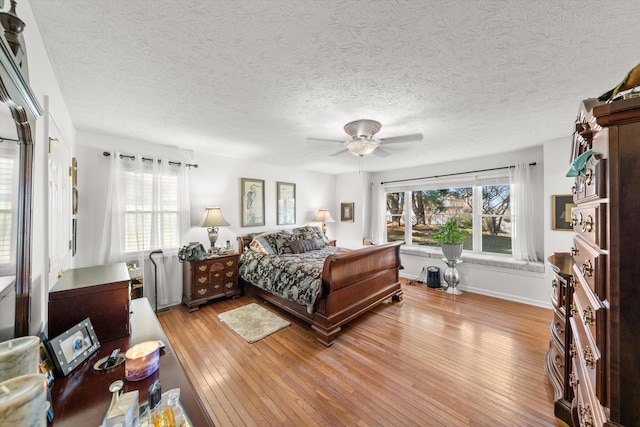 bedroom featuring ceiling fan, light hardwood / wood-style flooring, and a textured ceiling