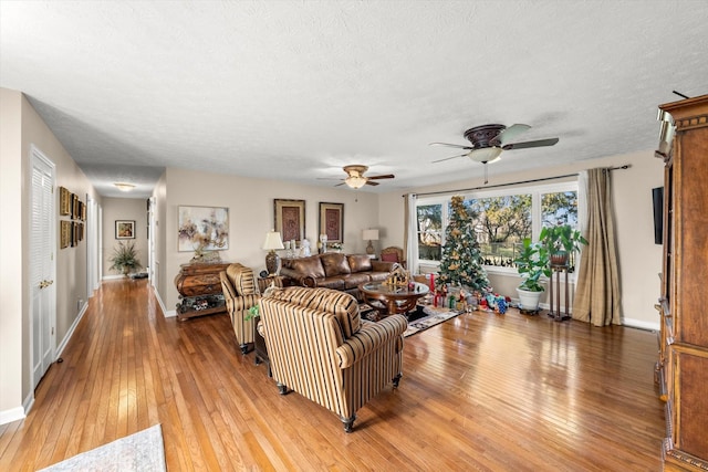 living room featuring wood-type flooring, a textured ceiling, and ceiling fan