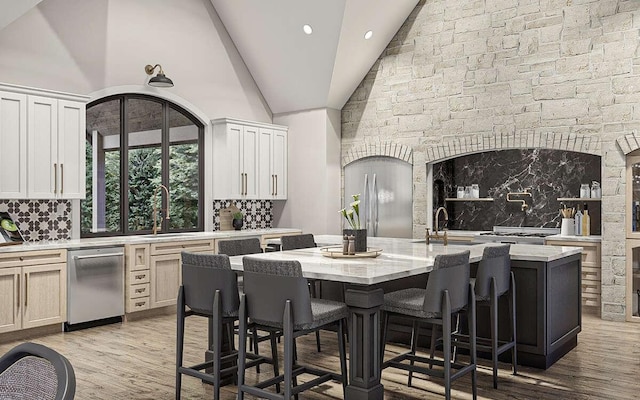 interior space featuring sink, decorative backsplash, stainless steel dishwasher, a kitchen island with sink, and a breakfast bar