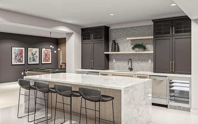 kitchen featuring light stone countertops, tasteful backsplash, sink, billiards, and a center island