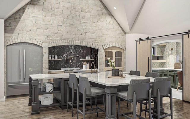 dining space with hardwood / wood-style floors, a barn door, high vaulted ceiling, and sink