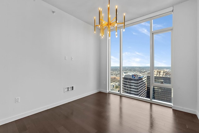 spare room with expansive windows, dark hardwood / wood-style flooring, and a chandelier