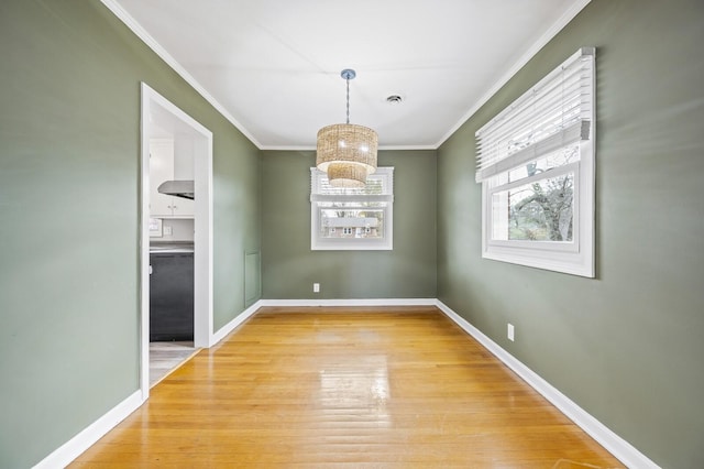 unfurnished dining area featuring ornamental molding and light hardwood / wood-style flooring