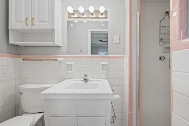 bathroom with vanity, toilet, and tile walls