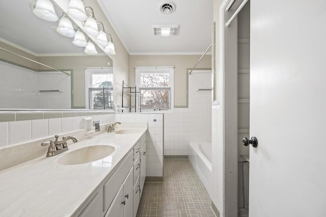 bathroom with ornamental molding, tile patterned floors, vanity, tile walls, and tiled shower / bath