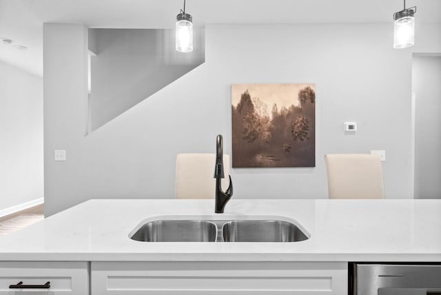 kitchen featuring white cabinetry, hanging light fixtures, and sink