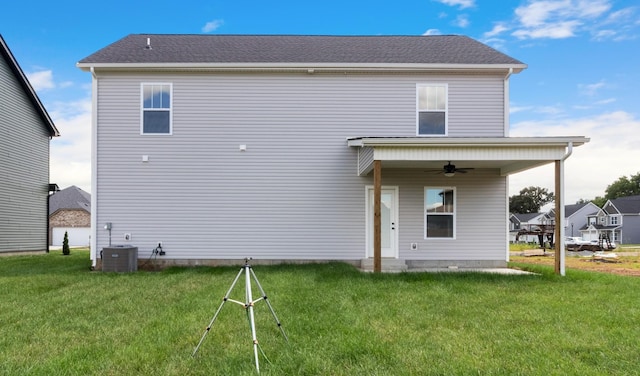 rear view of house with central AC, ceiling fan, and a yard