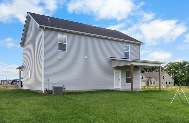 back of property with a lawn, ceiling fan, and central AC unit