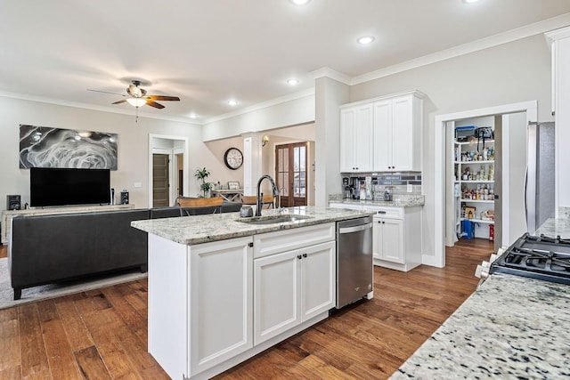 kitchen featuring light stone countertops, stainless steel appliances, sink, white cabinets, and an island with sink