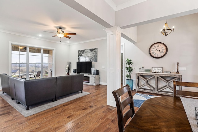 living room featuring hardwood / wood-style floors, ceiling fan with notable chandelier, ornate columns, and ornamental molding