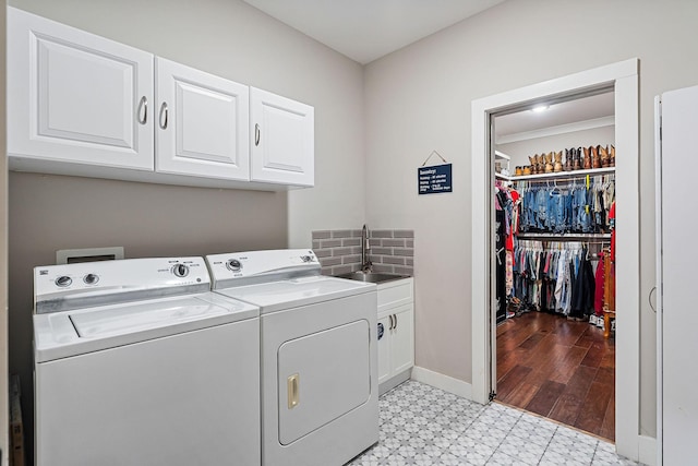 clothes washing area featuring washer and clothes dryer, cabinets, and sink