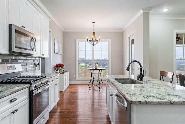 kitchen with stainless steel appliances, a kitchen island with sink, sink, an inviting chandelier, and white cabinetry